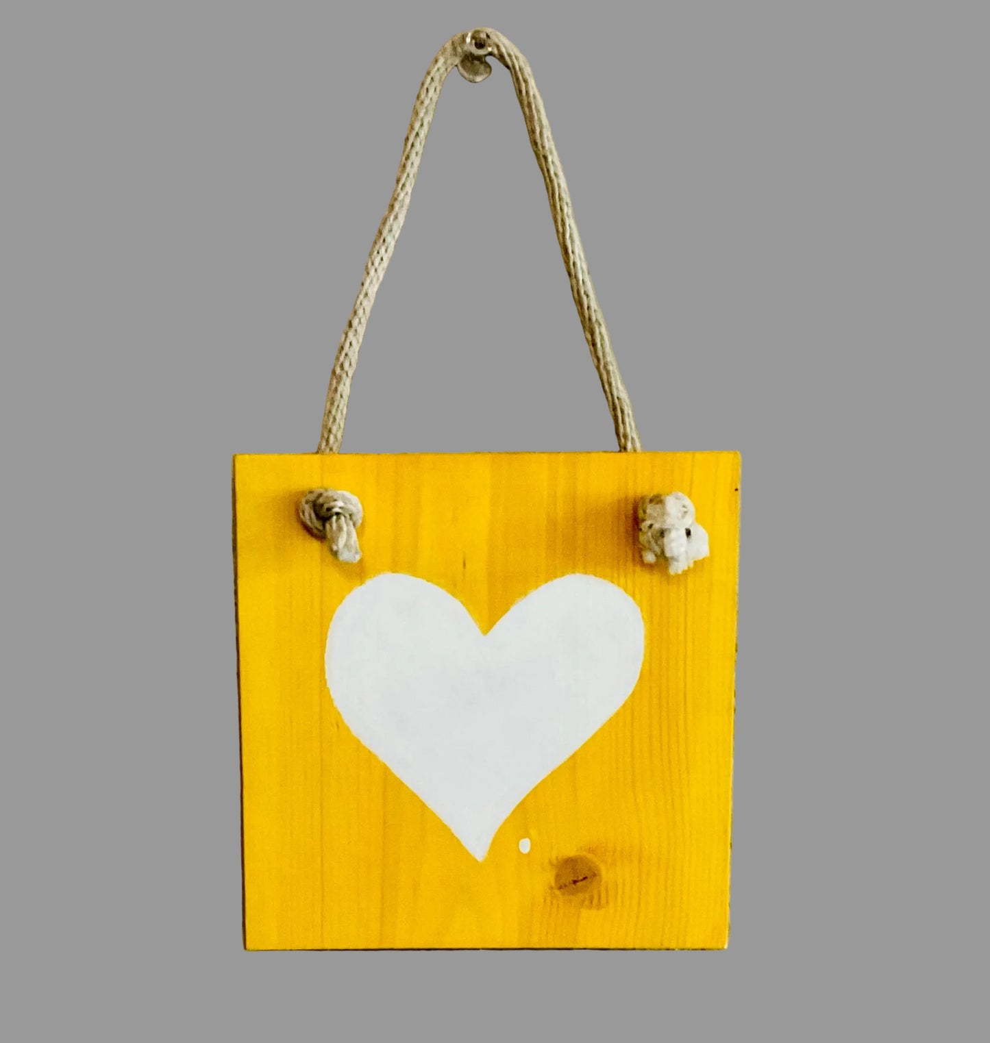 Yellow wooden sign with a white heart on a textured wall